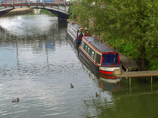 Fototapeta na wymiar River view with mooring narrowboats and a bridge in Tewkesbury in Gloucestershire, Great Britain.
