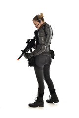 full length portrait of female  soldier wearing black  tactical armour, standing  with back to the camera holding a gun, isolated on white studio background.