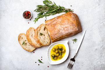 Italian ciabatta bread cut in slices with herbs and olives - obrazy, fototapety, plakaty
