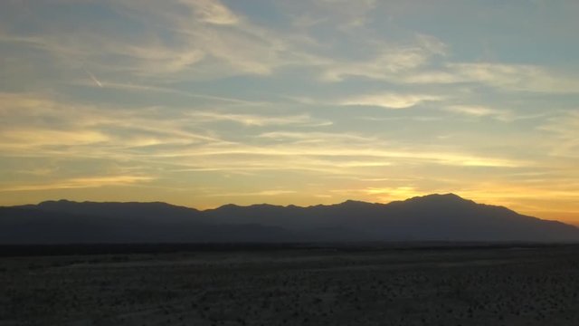 Aerial panning shot across mountains on the horizon at sunset in Palm Desert