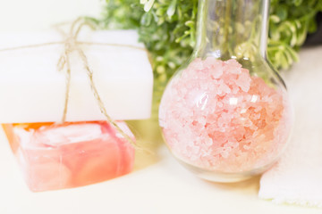 Aromatherapy spa concept. A glass bowl of orange bath salt, green leaves, a bar of fruit soap, closeup