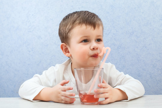 Cute Little Boy Drinking Juice On Light Blue Background. Lovely Kid Drink Grape Juice.