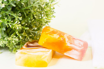 Aromatherapy spa concept. A glass bowl of orange bath salt, green leaves, a bar of fruit soap, closeup