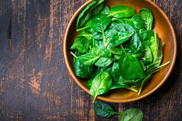 Baby spinach leaves in a bowl on dark background