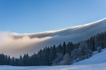 Winterlandschaft mit schnee und Nebel am Berg und blauem Himmel
