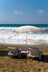 Sun beds are on the beach during a small storm.