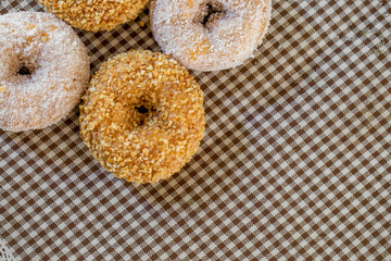 The group of peanut donut and coconut donut on the tablecloth in the natural light on the table by close up style.