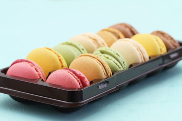 Selection of colorful macaroons in plastic box
