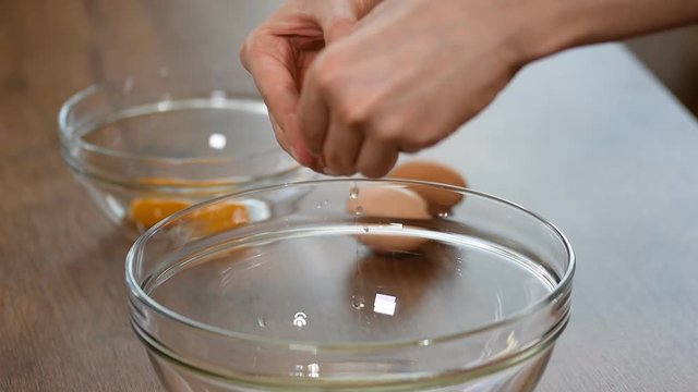 Female hands breaking an egg and separating yolk from white.