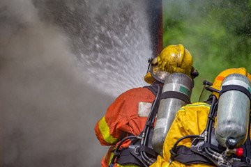 two firefighters water spray high pressure nozzle to fire and smoke with copy space
