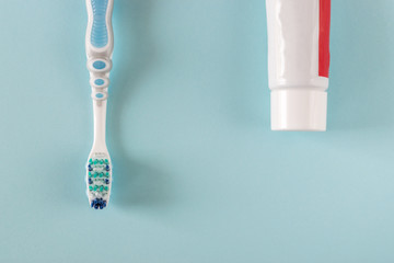 Toothbrush and toothpaste on bright blue background.