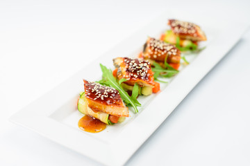 Sushi rolls with sesame seeds on a white plate, high cuisine