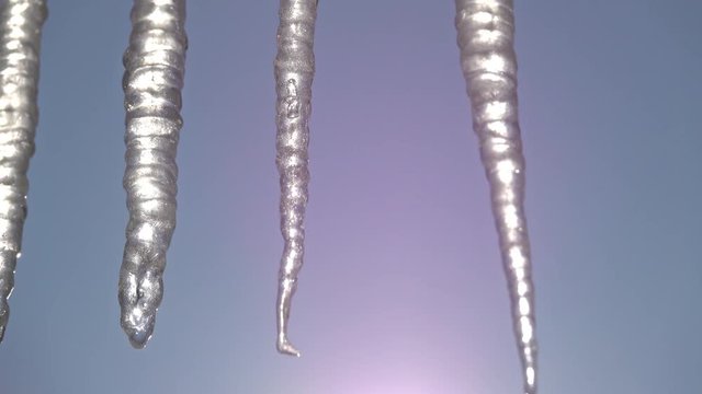 Zoom to closeup of icycles from a roof in a sunny day
