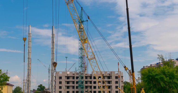 Many of cranes. Tower cranes against blue sky, with clouds. Timelapse.