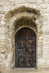 Large, beautiful wooden door in the wall of the old building. Close up.
