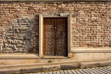 Large, beautiful wooden door in the wall of the old building. Close up.