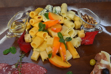 Assorted sliced cheese with mildew, blue, brie, swiss , cheddar, maasdam on the wooden background. fruit and olive oil