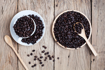 Fototapeta na wymiar coffee beans with coffee cup on old wooden plank background.