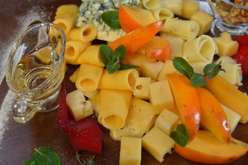 Assorted sliced cheese with mildew, blue, brie, swiss , cheddar, maasdam on the wooden background. fruit and olive oil