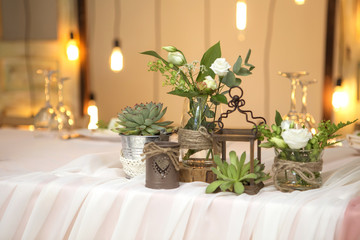 Simple but luxury rich table setting for a wedding celebration in nice cozy restaurant. Wineglasses, plates and bouquet of summer seasonal flowers on a table. Sunlight from a window. Copy space
