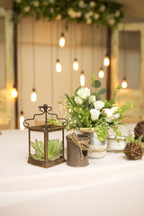 Simple but luxury rich table setting for a wedding celebration in nice cozy restaurant. Wineglasses, plates and bouquet of summer seasonal flowers on a table. Sunlight from a window. Copy space