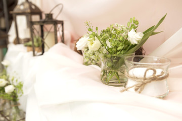 Simple but luxury rich table setting for a wedding celebration in nice cozy restaurant. Wineglasses, plates and bouquet of summer seasonal flowers on a table. Sunlight from a window. Copy space