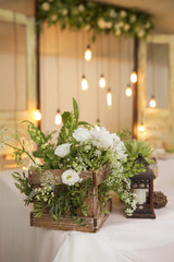 Simple but luxury rich table setting for a wedding celebration in nice cozy restaurant. Wineglasses, plates and bouquet of summer seasonal flowers on a table. Sunlight from a window. Copy space