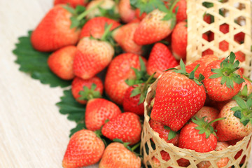 Fresh strawberries in a baske on the wood table blurred natural green background with copy space