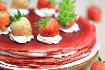 Stack of red velvet crepe cake with fresh strawberries