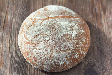 fresh rustic bread made of grey flour on wooden background