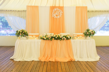 Simple but luxury rich table setting for a wedding celebration in nice cozy restaurant. Wineglasses, plates and bouquet of summer seasonal flowers on a table. Sunlight from a window. Copy space