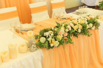 Simple but luxury rich table setting for a wedding celebration in nice cozy restaurant. Wineglasses, plates and bouquet of summer seasonal flowers on a table. Sunlight from a window. Copy space