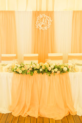 Simple but luxury rich table setting for a wedding celebration in nice cozy restaurant. Wineglasses, plates and bouquet of summer seasonal flowers on a table. Sunlight from a window. Copy space