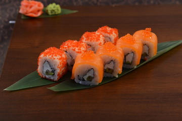 Sushi roll with salmon and shrimp tempura on the leaf. wodden background
