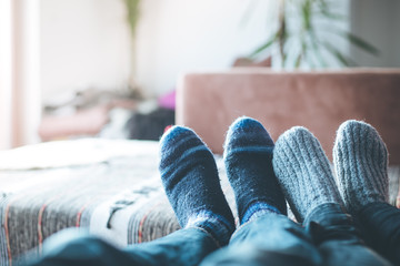 Junges paar liegt gemütlich auf der Couch, Füße mit Wollsocken, Winter