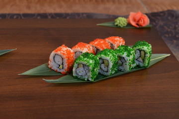 Sushi roll with salmon and shrimp tempura on the leaf. wodden background