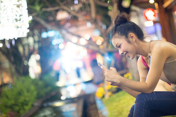 beautiful young woman using smart phone on a background with bokeh lights