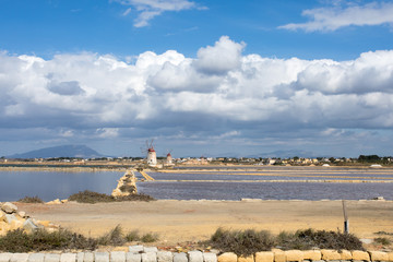 Marsala,Trapani - Sicilian salt lakes with wind mills and salt piles, during a sunny day with blue sky and clouds.