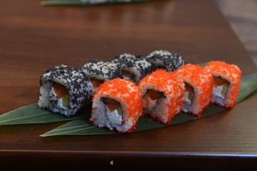 Sushi roll with salmon and shrimp tempura on the leaf. wodden background