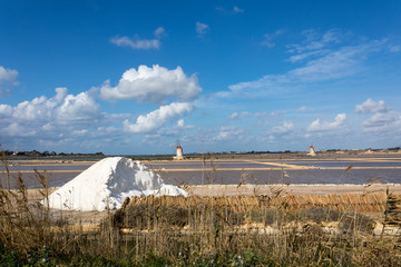 Marsala,Trapani - Sicilian salt lakes with wind mills and salt piles, during a sunny day with blue sky and clouds.