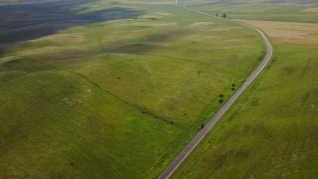 Road among green fields in Cherkessk, Karachaevo-Cherkessia. Beautiful view from above, shooting from a quadopter, 4K