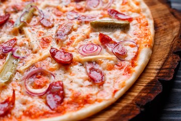 Appetizing pizza with salami, onions and gherkins and crunchy crust, close up. Food background