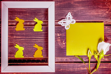 Happy Easter mockup. close-up of wooden easter rabbits in photo frame. rose flowers on green card template with copy space. easter sale, greeting and celebration card concept. easter border