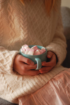 cozy dreams: the lovely girl holds a blue cup with pink marshmallow in her hands