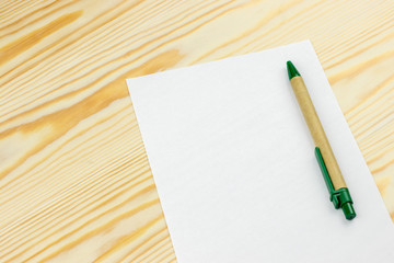 Sheet of white paper mockup with pen on wooden background
