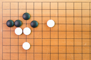 Game's white and black stone on cross board.