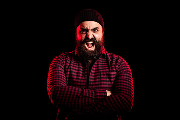 Bearded man screaming in anger on black background in studio photo