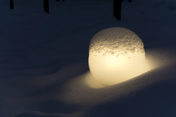 glowing round matte lantern in a snowdrift, reminiscent of a fallen moon