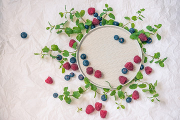 plate decorated with mint leaves and fresh berries of raspberries and berries