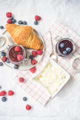 breakfast with raspberry and blueberry jam, croissants and cottage cheese